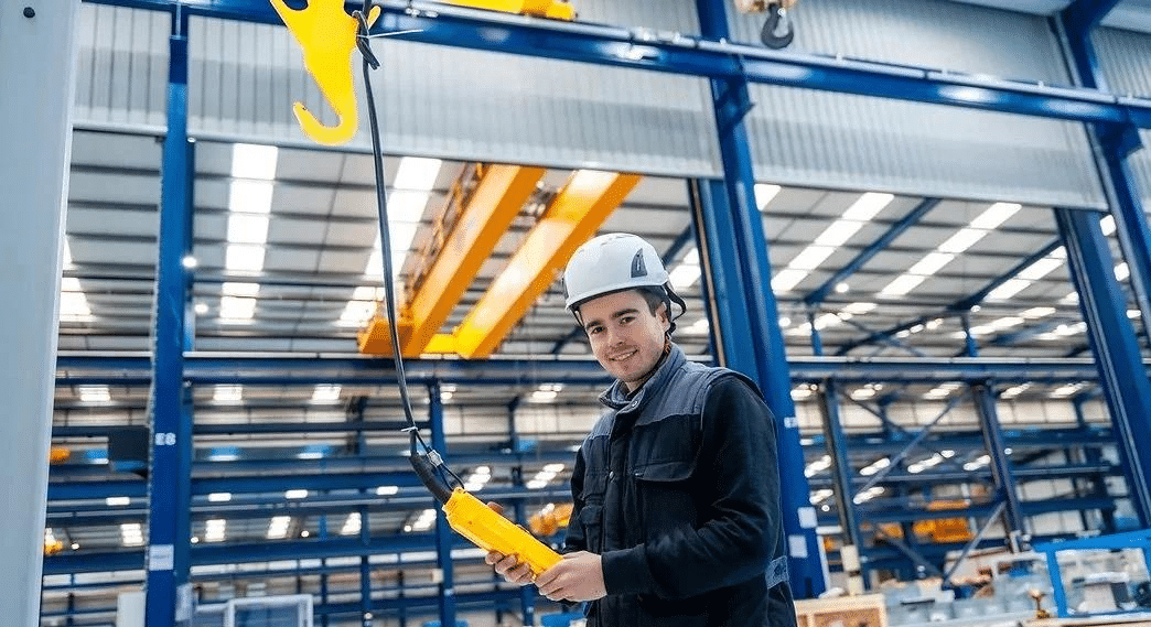 Operador utilizando control inalámbrico para manejo de cargas industriales.